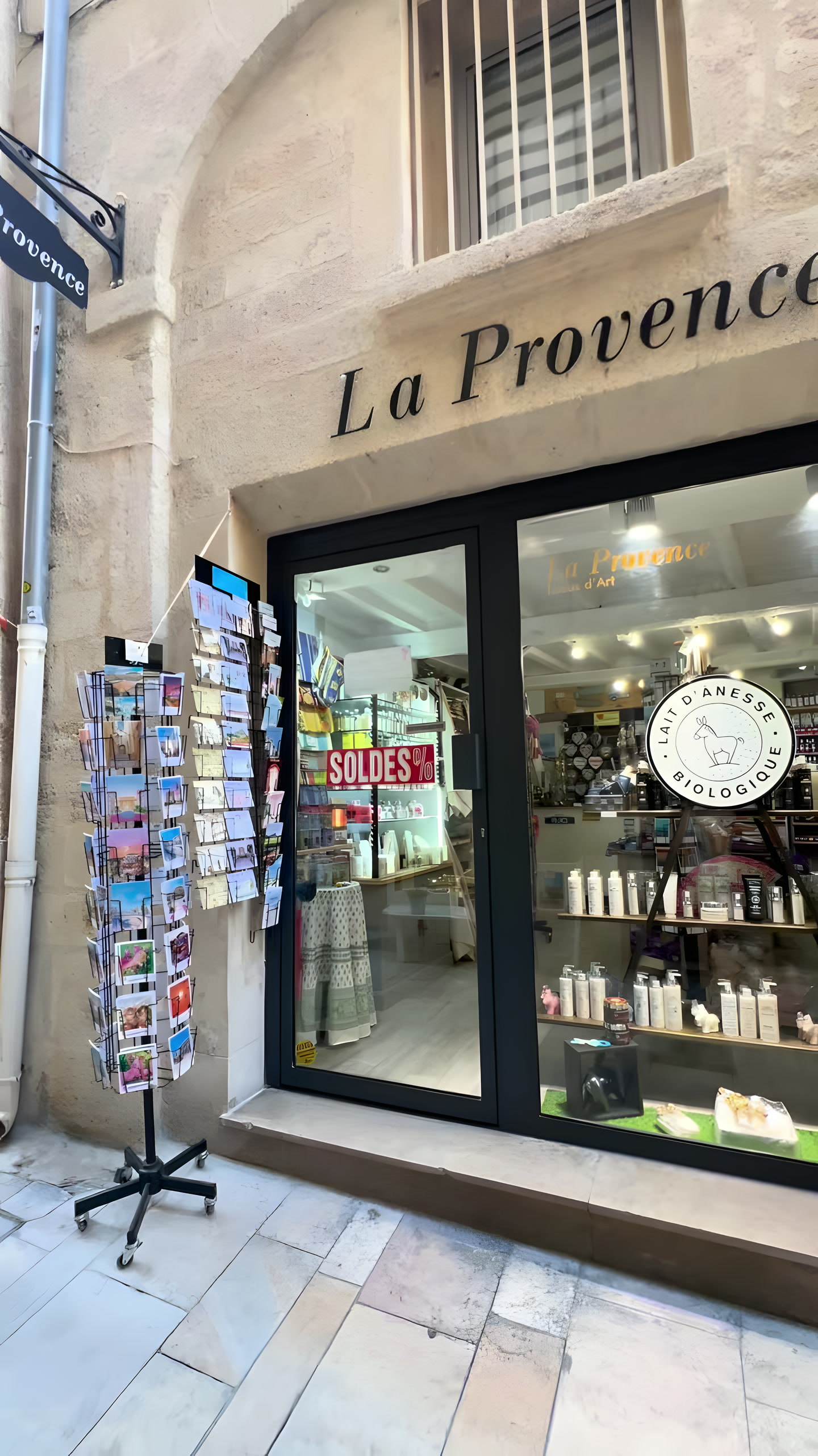 La devanture de la boutique : enseigne « La Provence » peinte sur la pierre, tourniquets de cartes postales